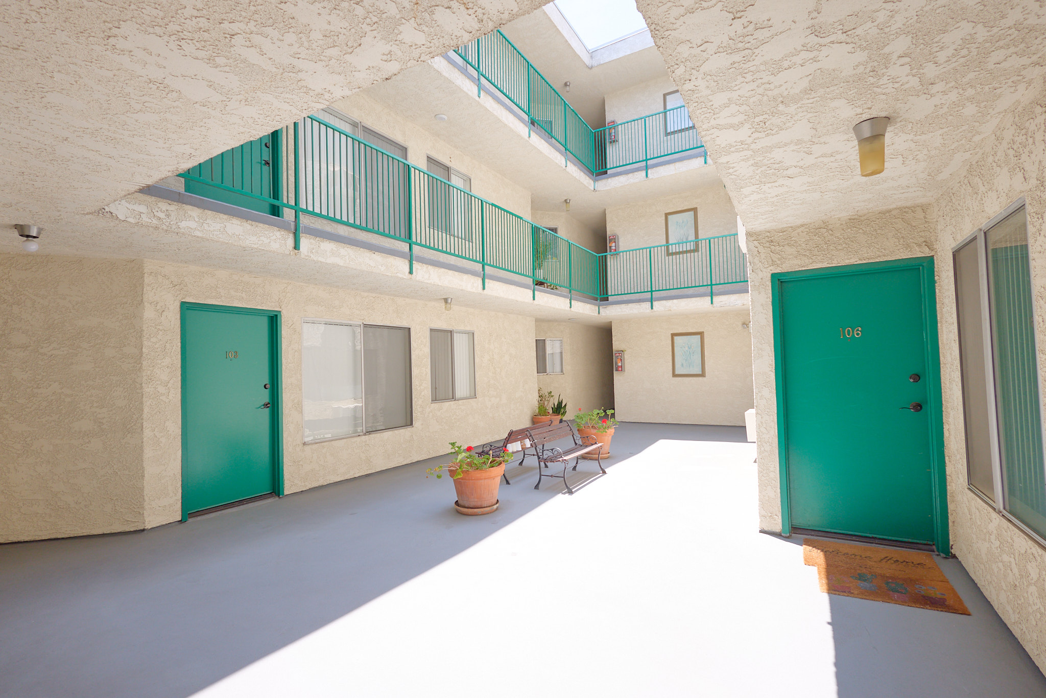 A balcony with green railings is on the second floor of a building.